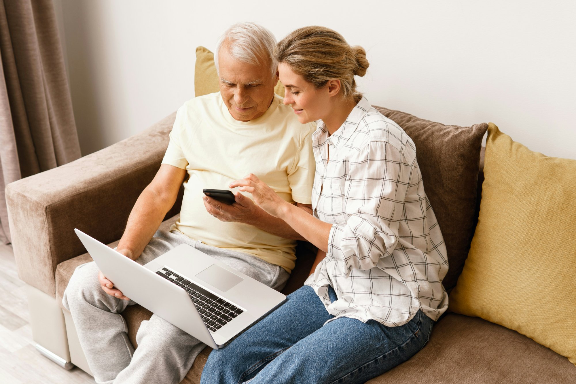 Senior man and young woman looking at a phone together on a couch